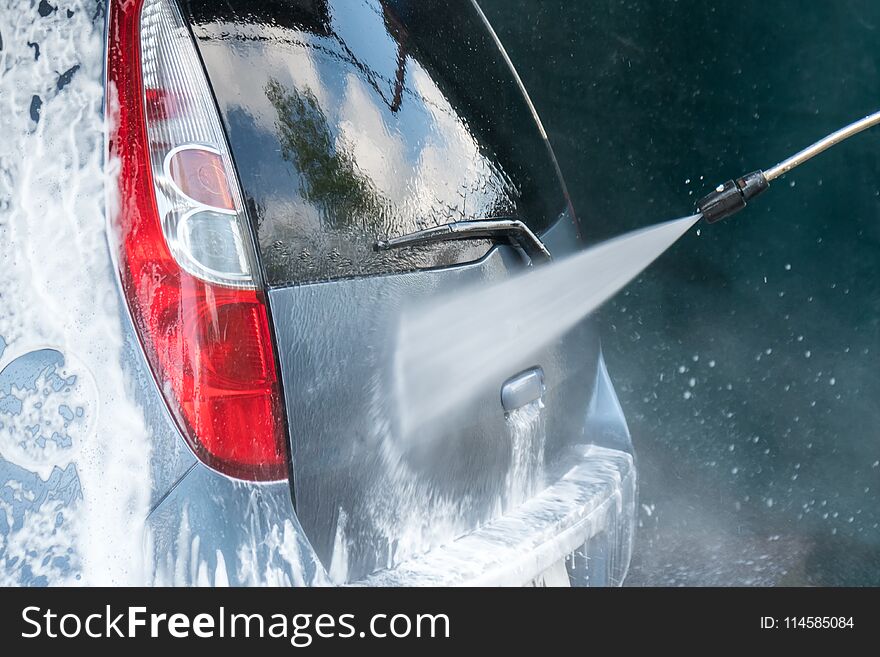 Car Wash Closeup. Washing Car by High Pressure Water.