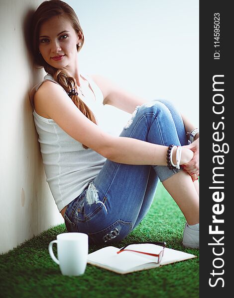 Beautiful woman sitting on the floor and holding a cup . Beautiful woman.