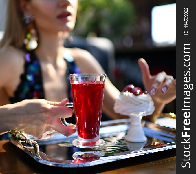 Woman in expensive interior restaurant cafe drinking red margarita cocktail or juice tea and eat dessert cake with strawberry