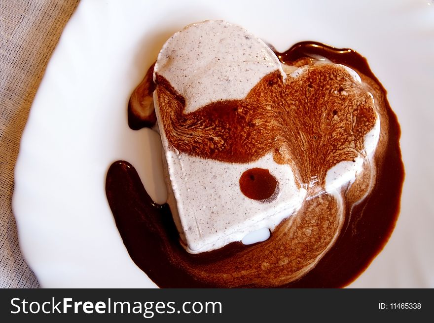 Ice-cream heart with chocolate sauce on a white plate