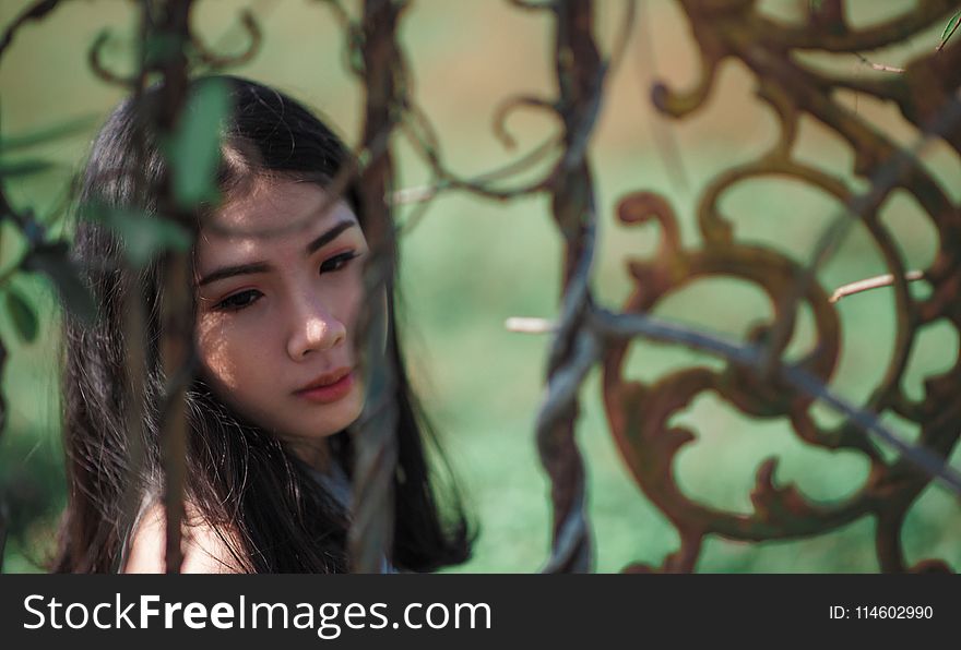 Woman With Green Background Near Black Metal Gate