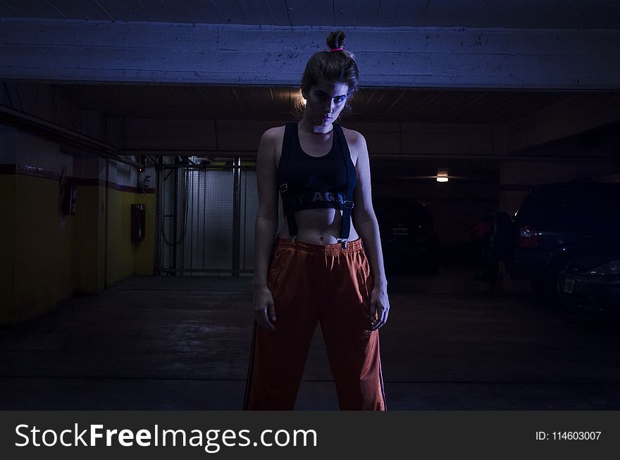 Woman With Black Sports Bra And Red Pants In Dark Room