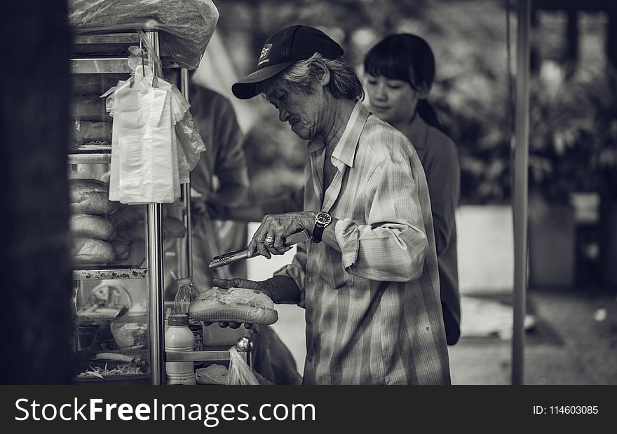 Grayscale Photo of a Man Selling Sandwiches on the Streets