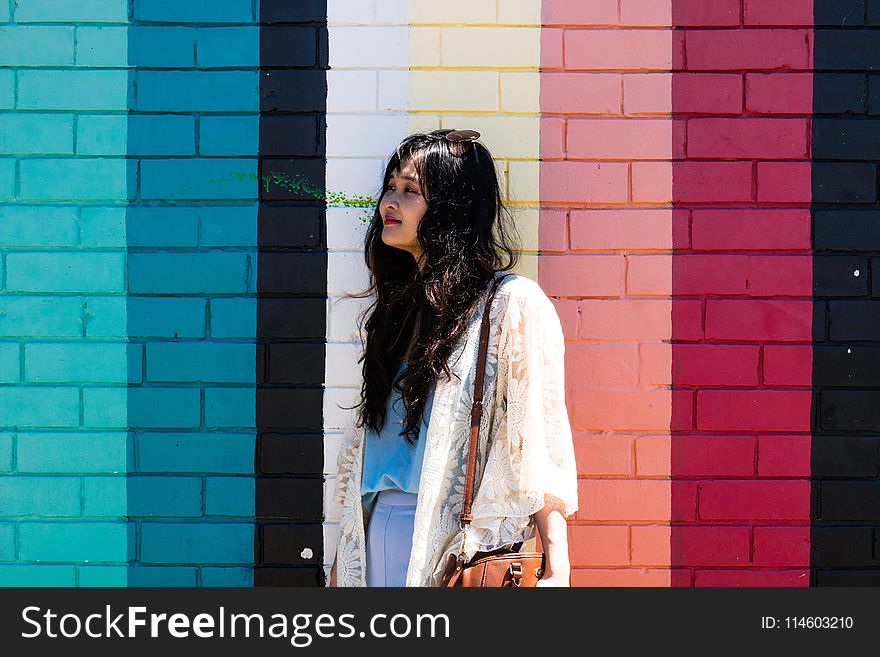 Woman Wearing White Cardigan Standing Beside Multicolored Wall