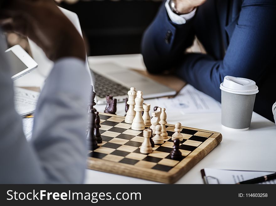 Photo Of Brown Wooden Chess Set On Table Beside White And Gray Disposable Cup