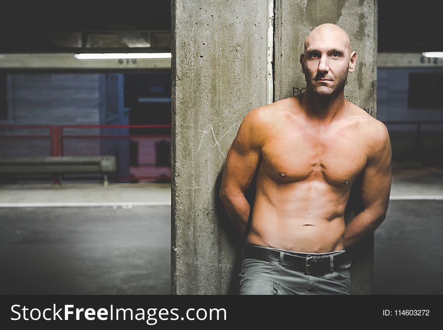 Photography of a Shirtless Man Leaning on Wall