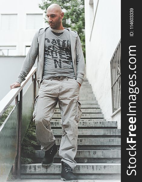 Photo of Man Wearing Grey Zip-up Jacket and Brown Cargo Pants Walking Down on Concrete Stairs