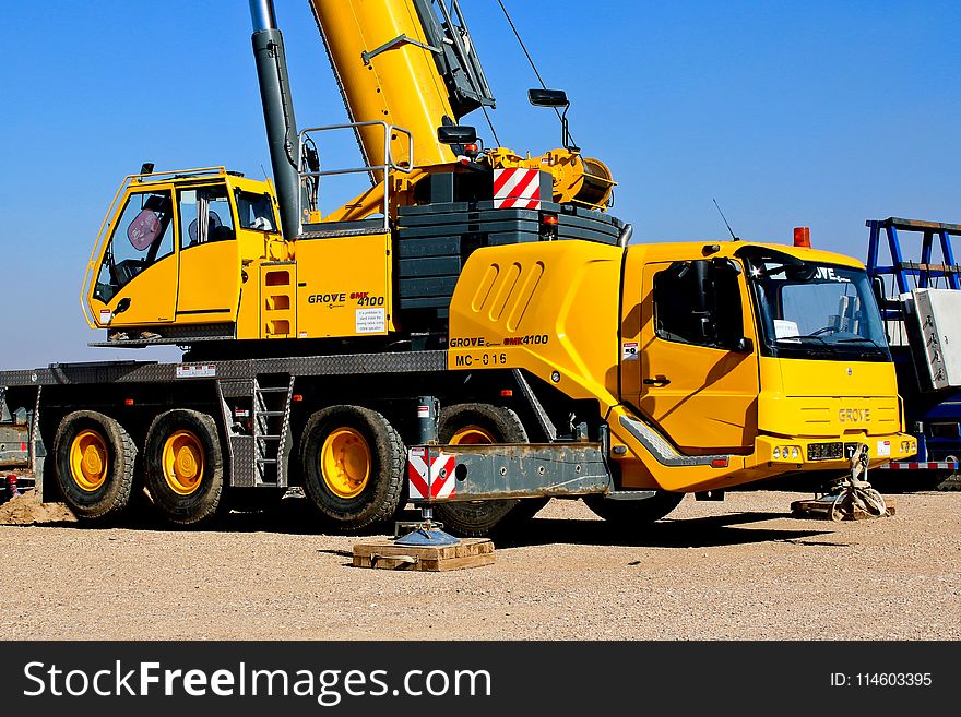 Yellow Crane Truck Parked On Brown Field