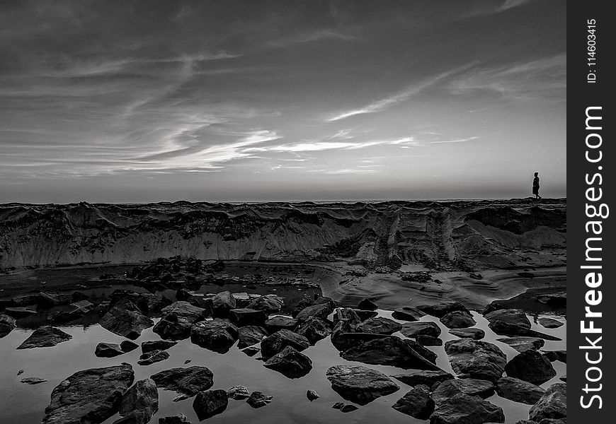 Grayscale Photo Of Person Walking On Rocks