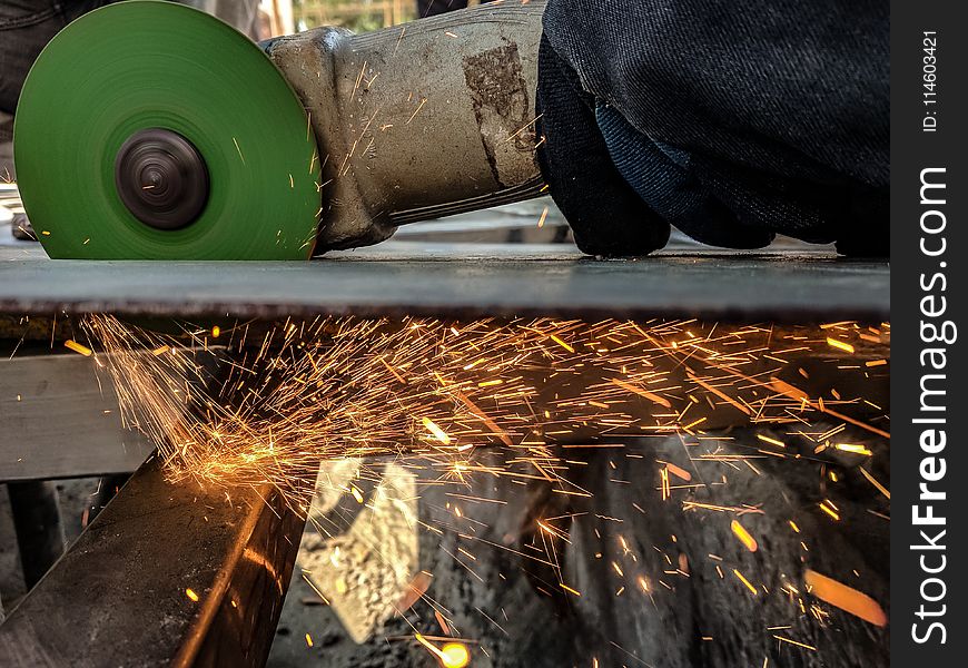 Person Using Green And Grey Angle Grinder On Sheet Of Metal