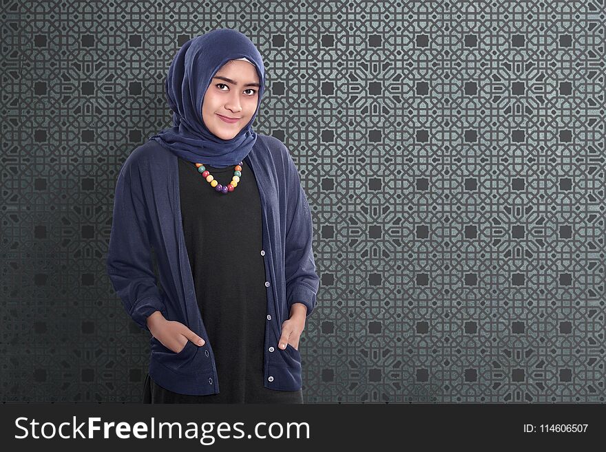 Smiling asian muslim female standing with traditional dress over abstract background