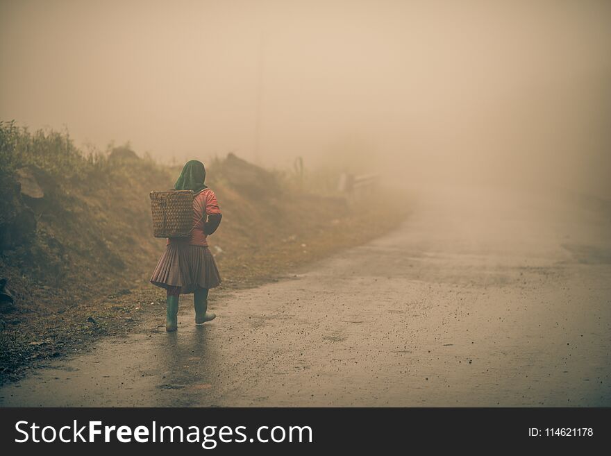 A farmer walks along a foggy road in vietnam