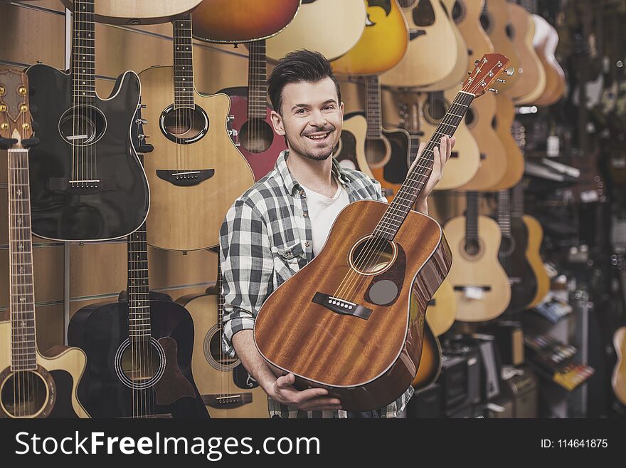 Man is showing guitar in music store.