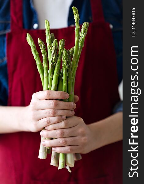 Hands of young woman holding a bunch of green asparagus.
