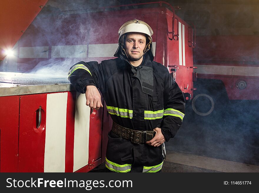 Fireman firefighter in action standing near a firetruck. Emergency safety. Protection, rescue from danger.
