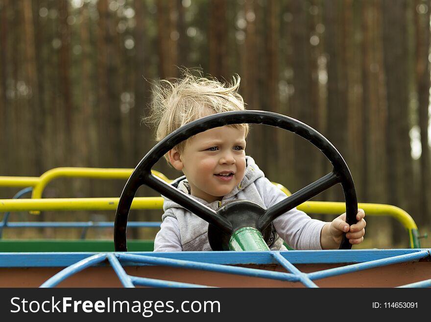 Cute Disheveled Toddler Sitting In The Toy Car Attraction In The Park