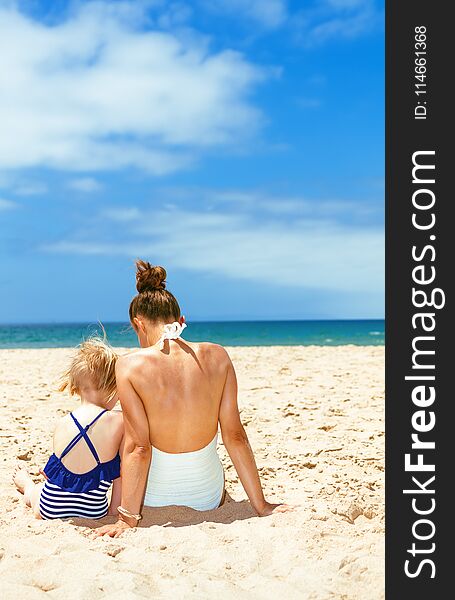 Seen From Behind Young Mother And Child In Swimwear On Beach