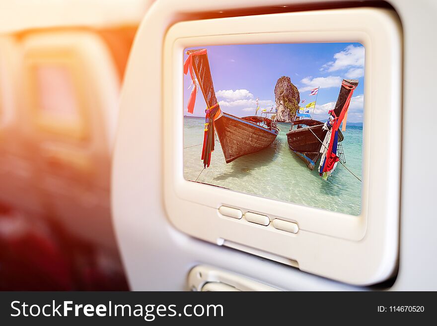 Aircraft In flight entertainment seat-back TV screens showing a picture of long tail boat and beautiful beach at Po-da Island, Andaman Sea, Krabi, South of Thailand.