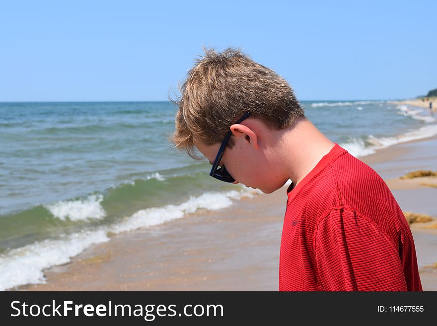 Photo of Boy Wearing Red Shirt and Sunglasses On Seashore