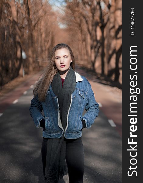 Woman Standing On Asphalt Road Surrounded By Bare Tree