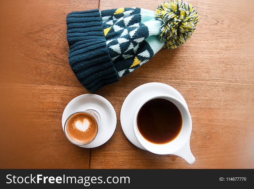 High Angle Photo Of Mug Filled With Coffee Beside Bobble Hat