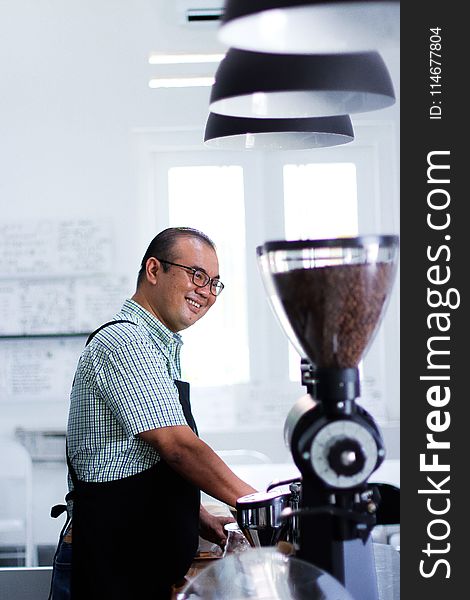 Man Wearing Plaid T-shirt And Black Apron in Front of Coffeemaker