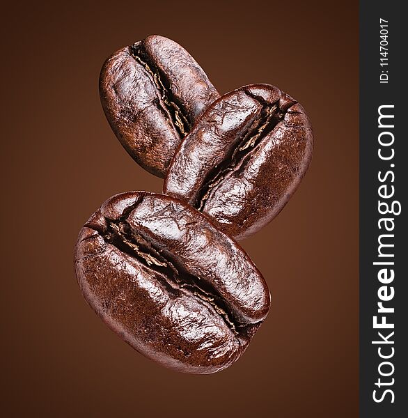 Three roasted coffee beans on the brown background. File clipping path. Three roasted coffee beans on the brown background. File clipping path.