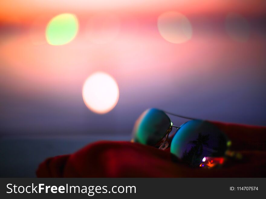 Summer poster with sunglasses, palms and bokeh effects. Blurred sunset beach background.