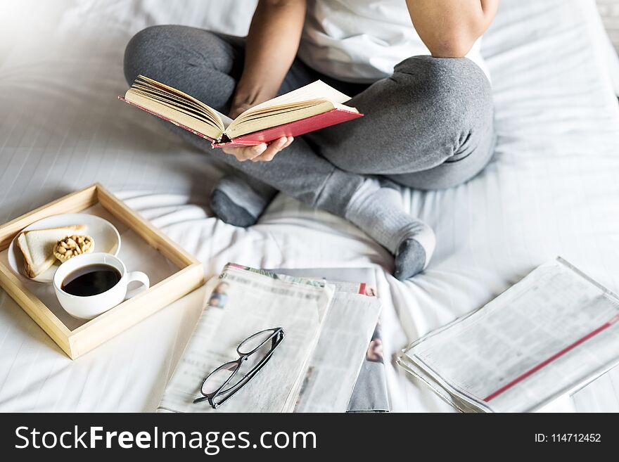 Woman reading book or newspaper and drinking coffee breakfast on