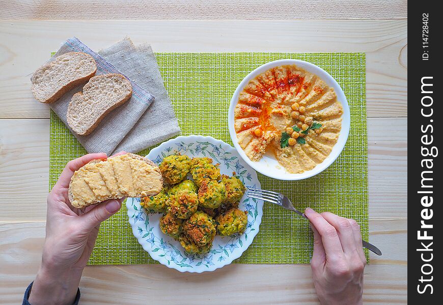 A plate of hummus and parsley on wooden background. The view from the top. A plate of hummus and parsley on wooden background. The view from the top.