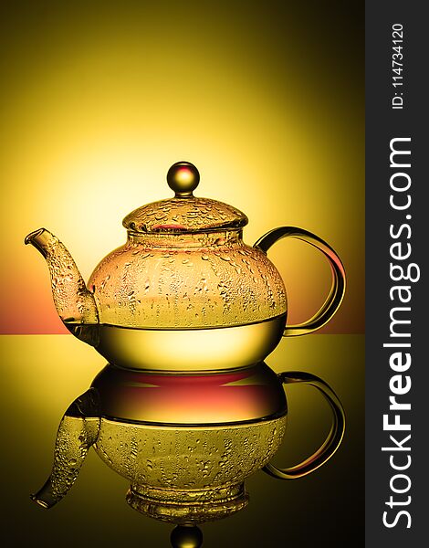 Glass teapot with boiling water and drops of condensation on glass advertising shot on light multy colored background with realistic reflection of gloss reflexes Close-up of macro with copy space.