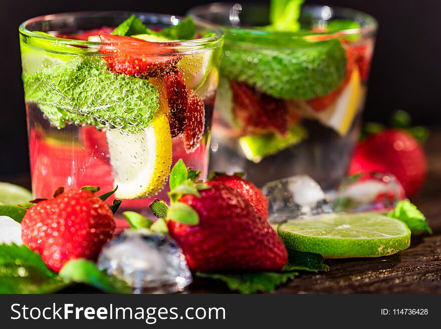 Close up glasses with strawberry mojito with lemon and mint on dark background. Selective focus. Summer drink concept. Close up glasses with strawberry mojito with lemon and mint on dark background. Selective focus. Summer drink concept