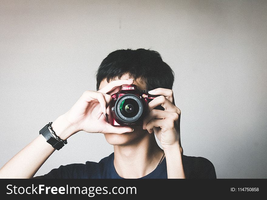 Man In Black Crew-neck Shirt Using Red Bridge Camera