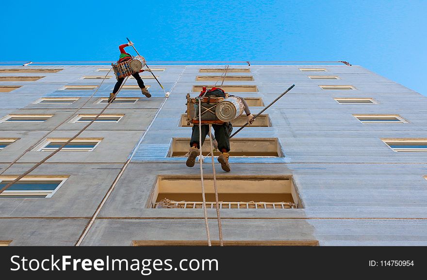 Two People Wearing Harnesses and Painting Building