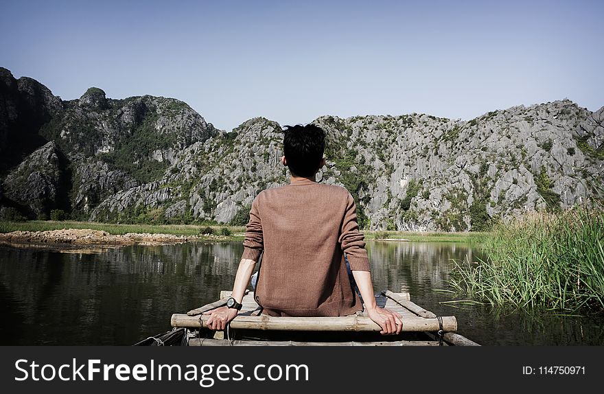 Man Sitting on Bridge Front of Mountain