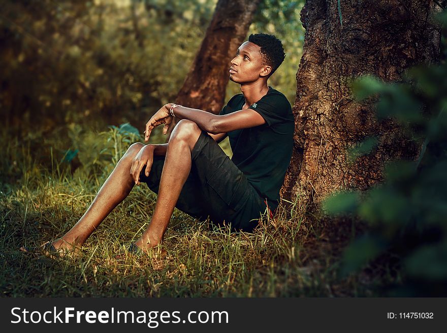 Man Seating Beside Tree Trunk