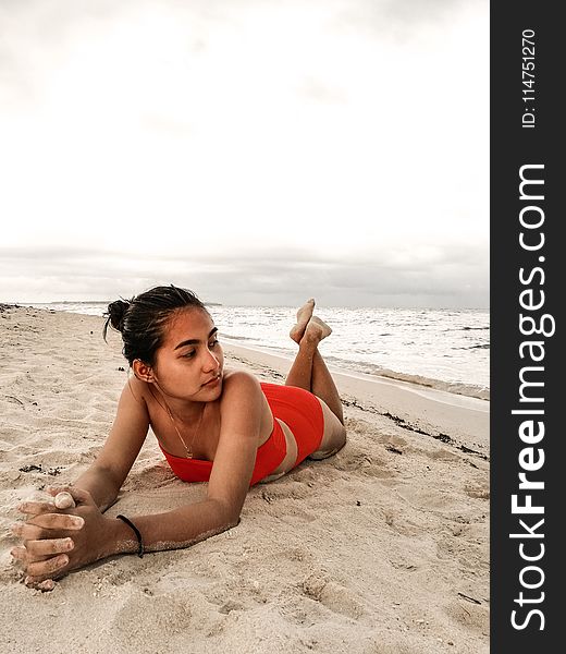 Woman Wearing Red Bikini Laying On Beach Sand