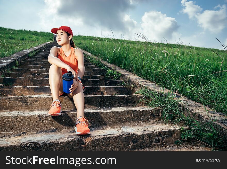 An asian woman athletic is jogging on the concrete road