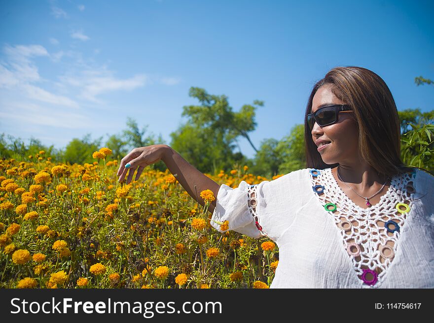 Happy and beautiful young Asian woman relaxing enjoying the fresh beauty of gorgeous orange marigold flowers field natural landscape in travel destination and holidays Summer trip tourist excursion