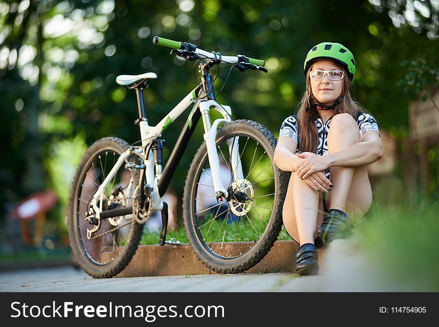 Female cyclist sitting near bike