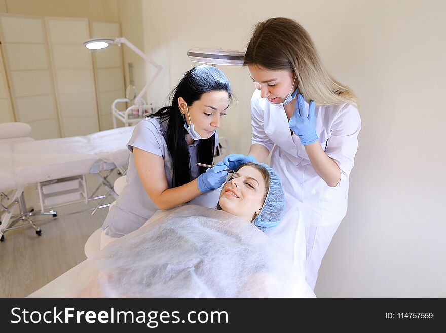 American cosmetologist and nurse making permanent makeup by tattoo pen. Concept of beauty industry. American cosmetologist and nurse making permanent makeup by tattoo pen. Concept of beauty industry.