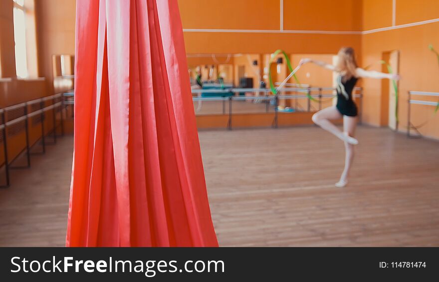 Red silk in front of young woman training a gymnastics exercise with a ribbon