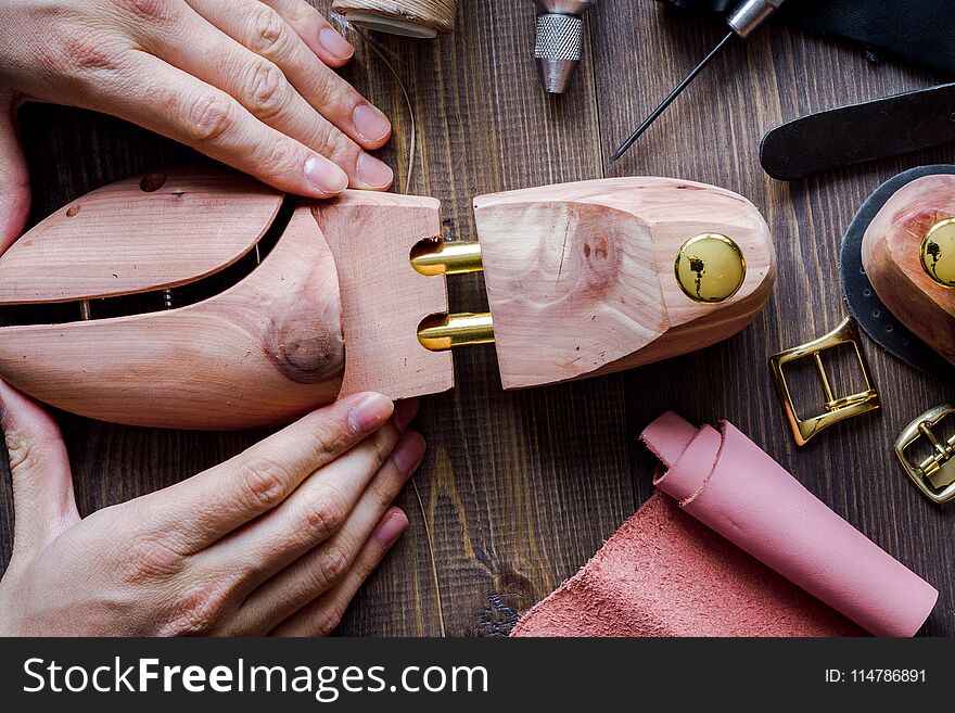 Cobbler tools in workshop on dark background top view with hands. Cobbler tools in workshop on dark background top view with hands