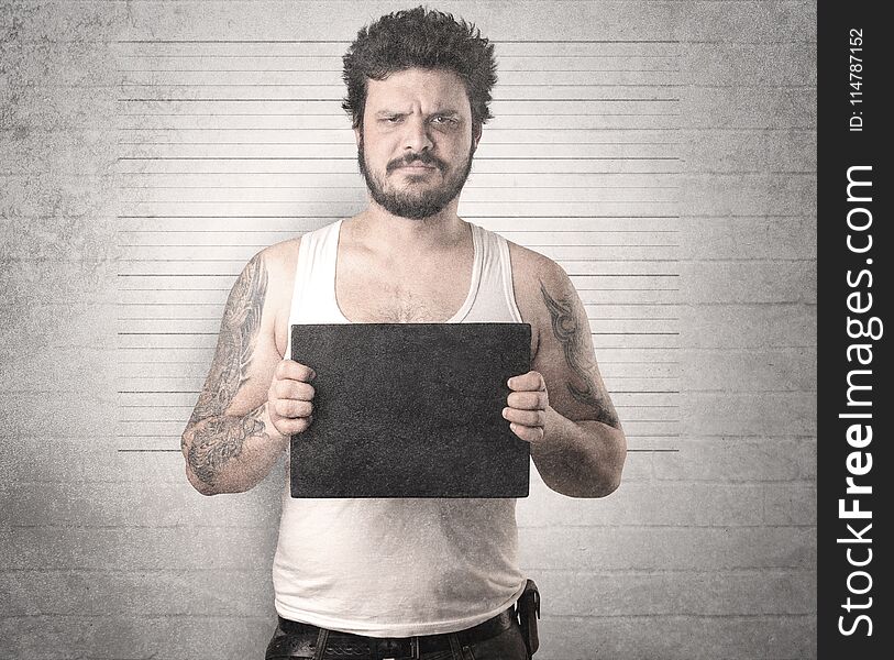 Gangster in front of a wall with table on his hand. Gangster in front of a wall with table on his hand.