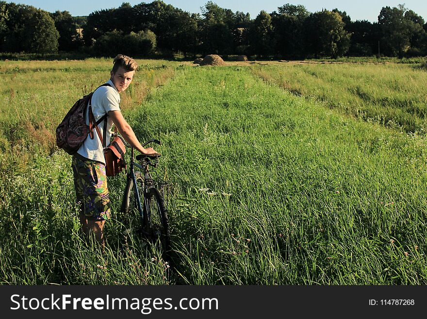 Boy holding and riding a bicycle in a field on a sunny summer da