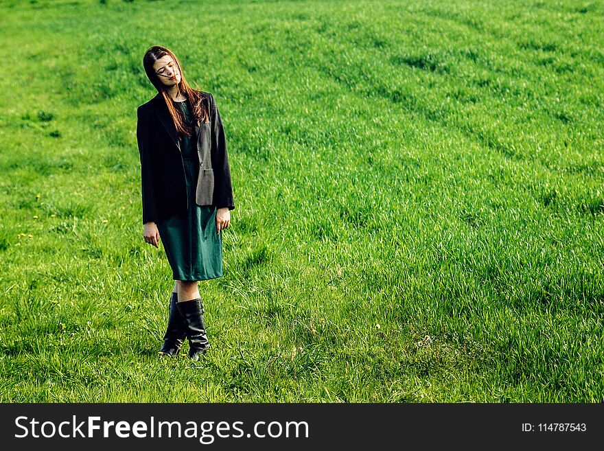 Beautiful brunette girl in windy green field, sunny springtime, environment concept