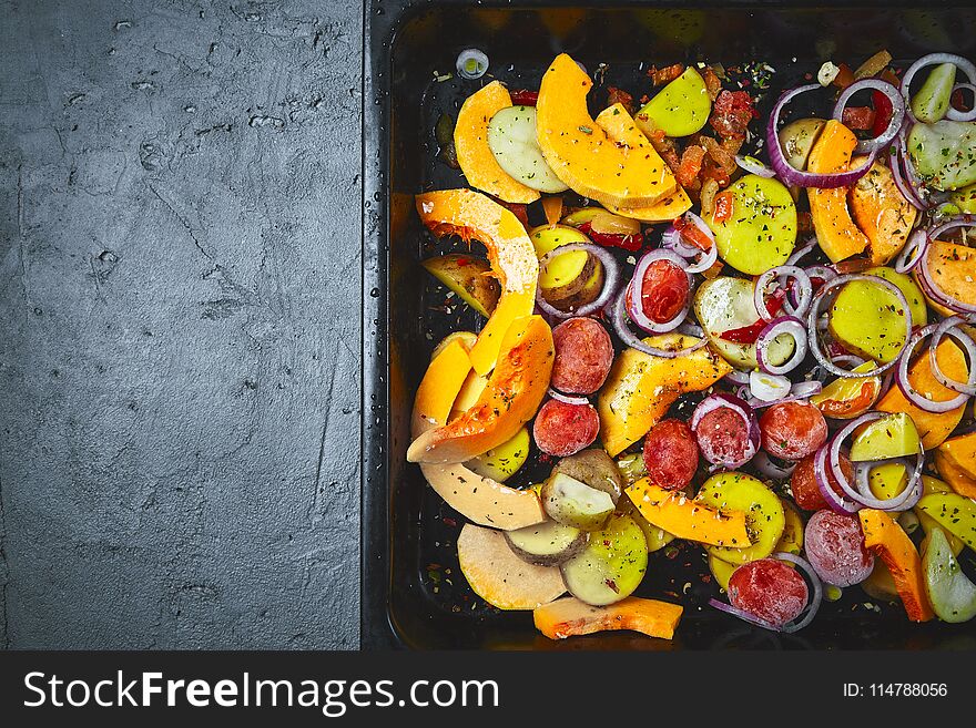 Raw sliced vegetables in baking tray on a black concrete or stone background. Top view .Space for text. Raw sliced vegetables in baking tray on a black concrete or stone background. Top view .Space for text.