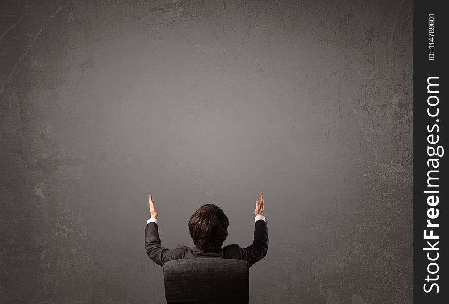 Young businessman sitting in office chair in front of a wall with empty space. Young businessman sitting in office chair in front of a wall with empty space