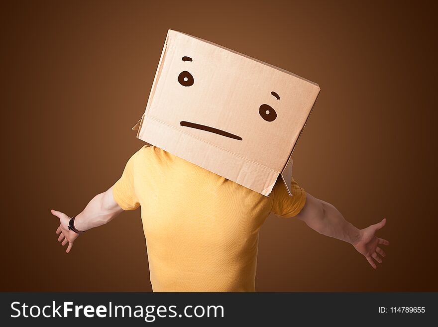 Young man gesturing with a cardboard box on his head with straight face