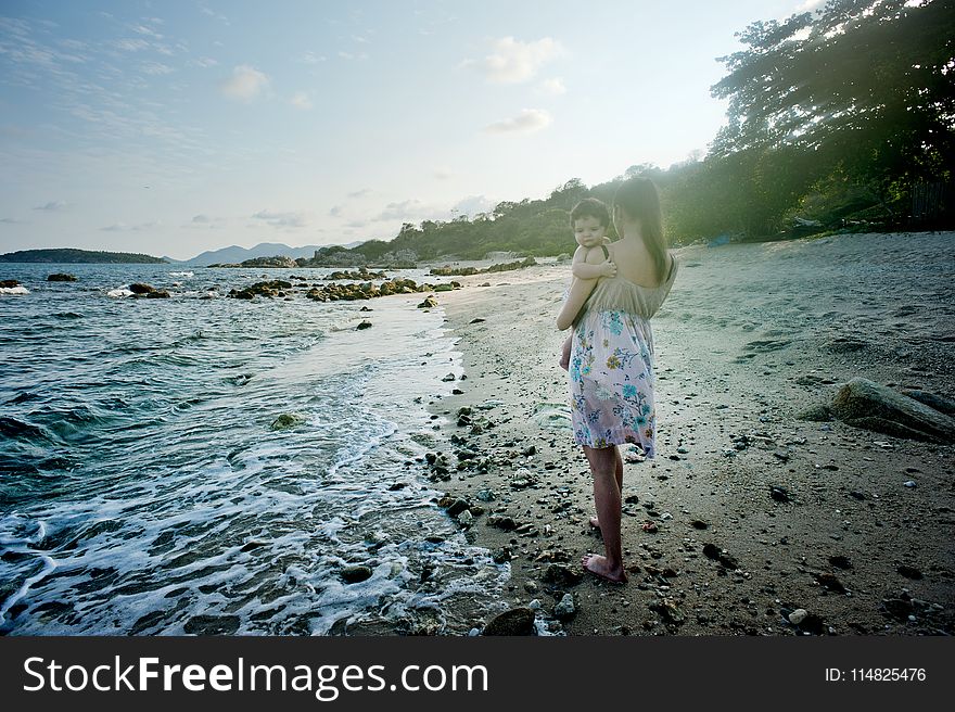 Woman Carrying Baby Beside the Seashore